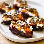 Hot honey and pistachio ricotta stuffed dates arranged on a white serving dish