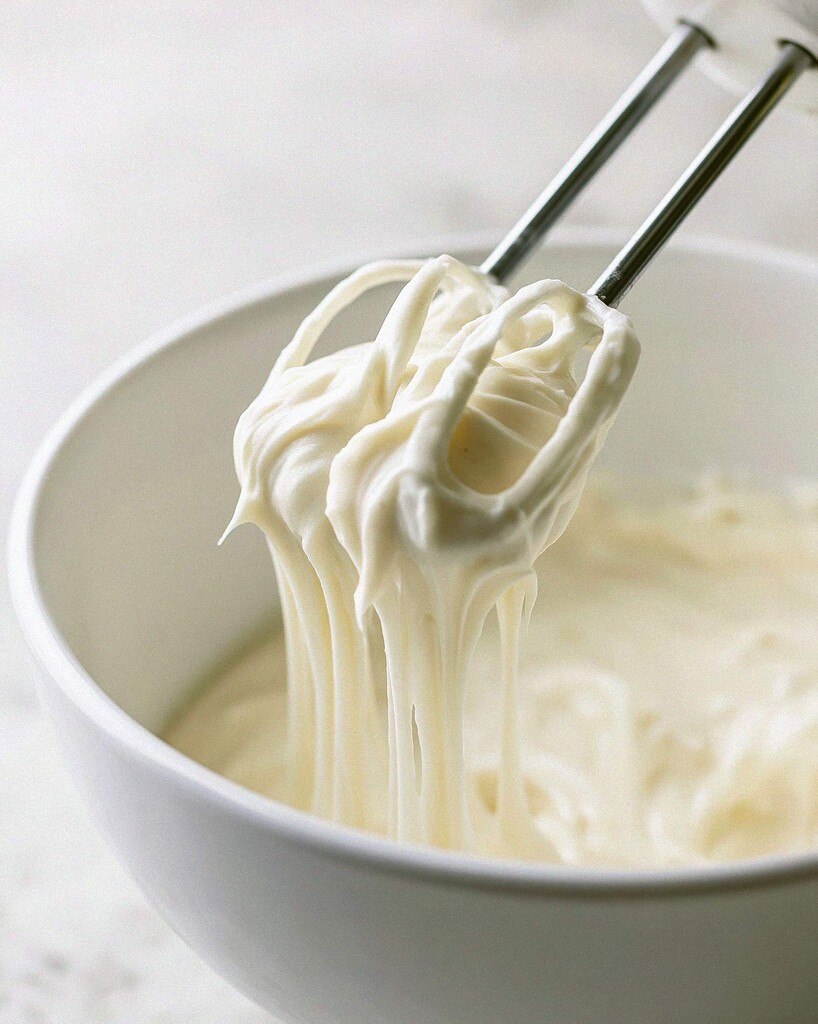 Creamy pale yellow banana pudding mixture being beaten with a hand mixer