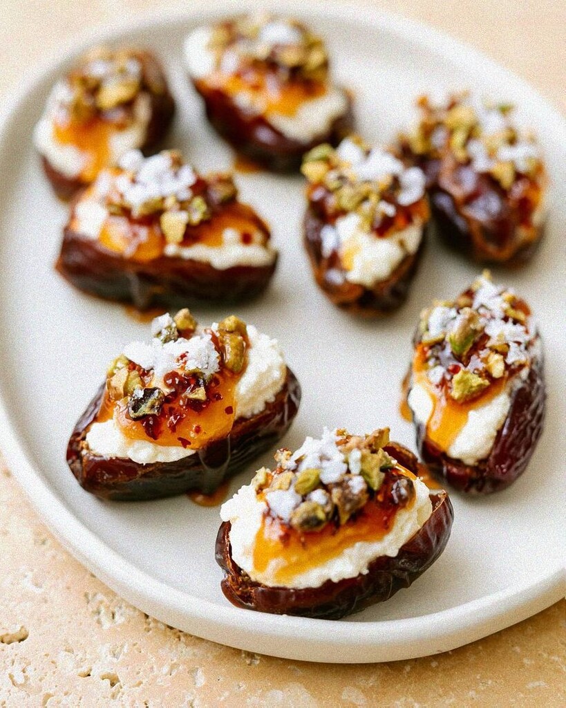 Arranging the ricotta filled dates on a white platter before garnishing