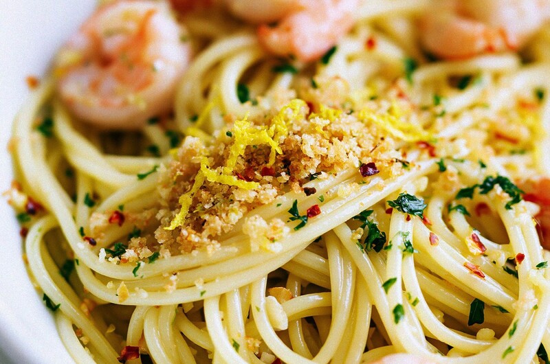 A serving of one-pan garlic butter shrimp pasta in a white bowl garnished with golden panko and fresh parsley