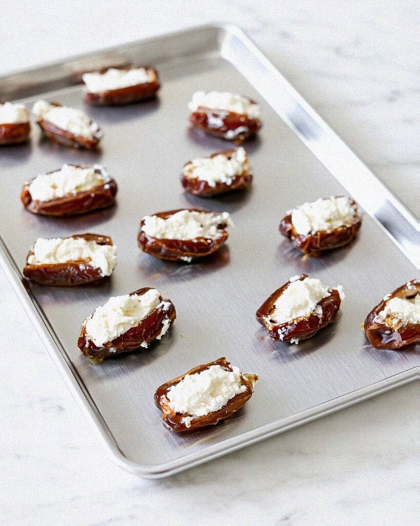 Medjool dates filled with smooth whipped ricotta resting on a metal prep tray