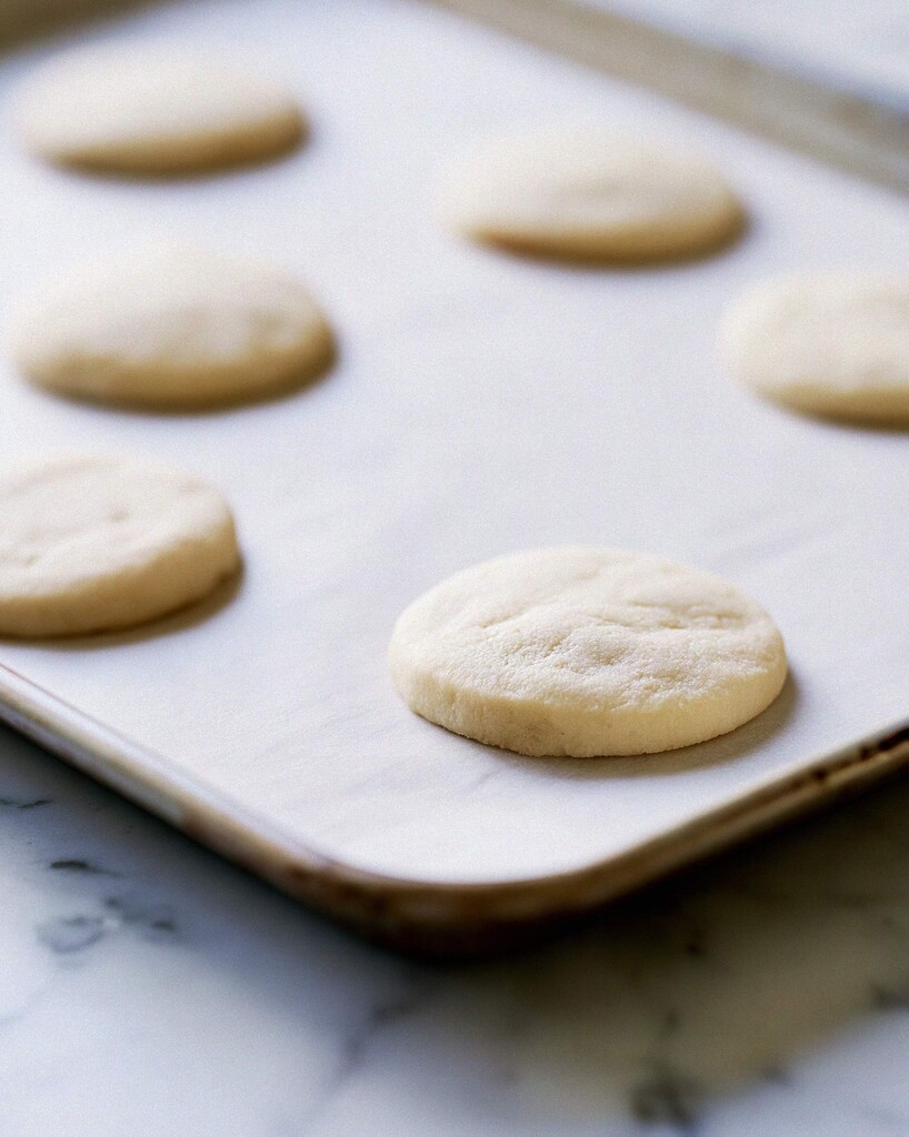Pale baked lemon meltaway cookies on a parchment lined baking sheet