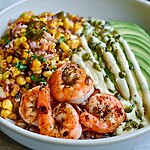 Grilled smoky shrimp bowl with charred corn, sliced avocado, and white crema over a bed of rice
