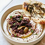 Za'atar naan with whipped feta topped with dark and green olives and chopped herbs in a ceramic dish