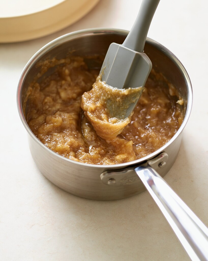 Mashed bananas simmering with dark brown sugar in a small stainless steel saucepan