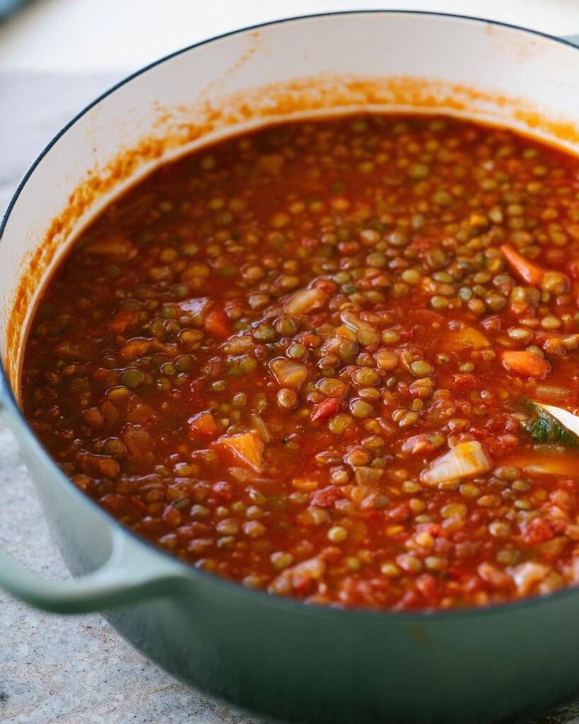 Thick Italian lentil soup boiling in a heavy cooking pot