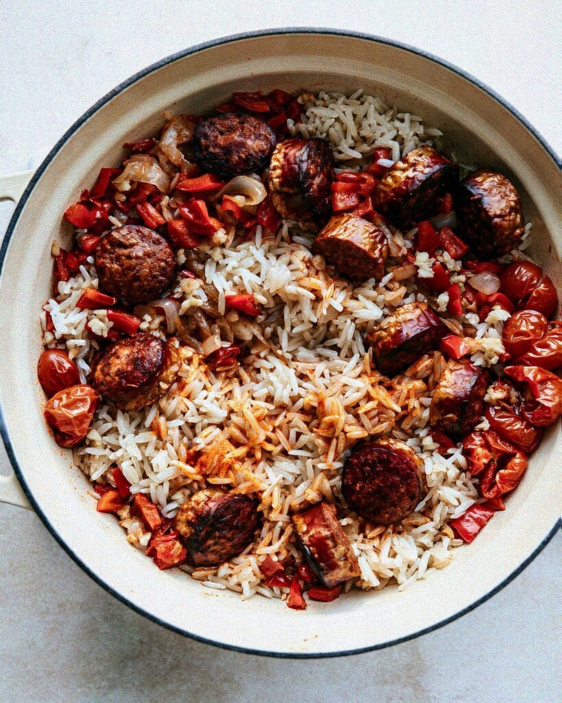 White rice stirred together with browned sausage, bell peppers, and tomatoes in a pot
