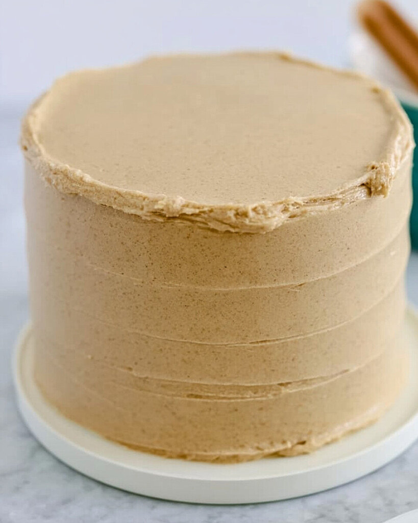 A two layer cake fully covered in smooth brown frosting with horizontal texture lines
