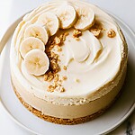 Whole caramelized banana pudding cheesecake topped with mousse, fresh bananas, and wafer crumbs