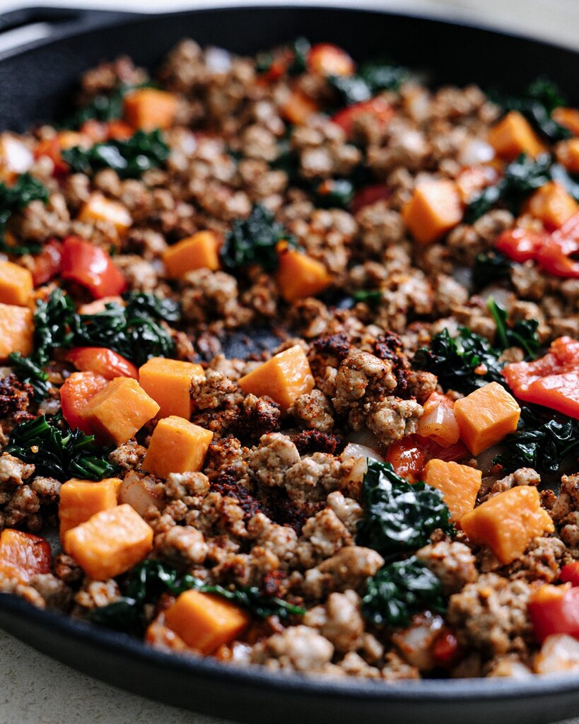 Ground turkey, sweet potatoes, and wilted kale mixed together in a pan