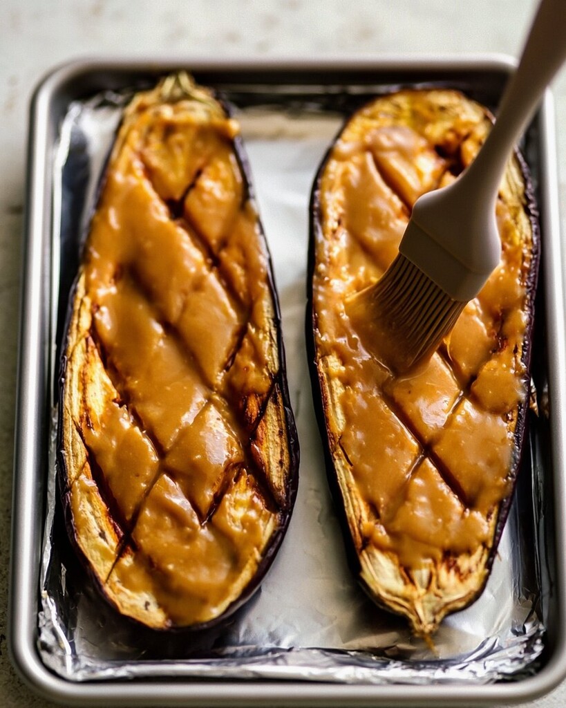 Brushing creamy miso glaze onto the scored and roasted eggplant halves
