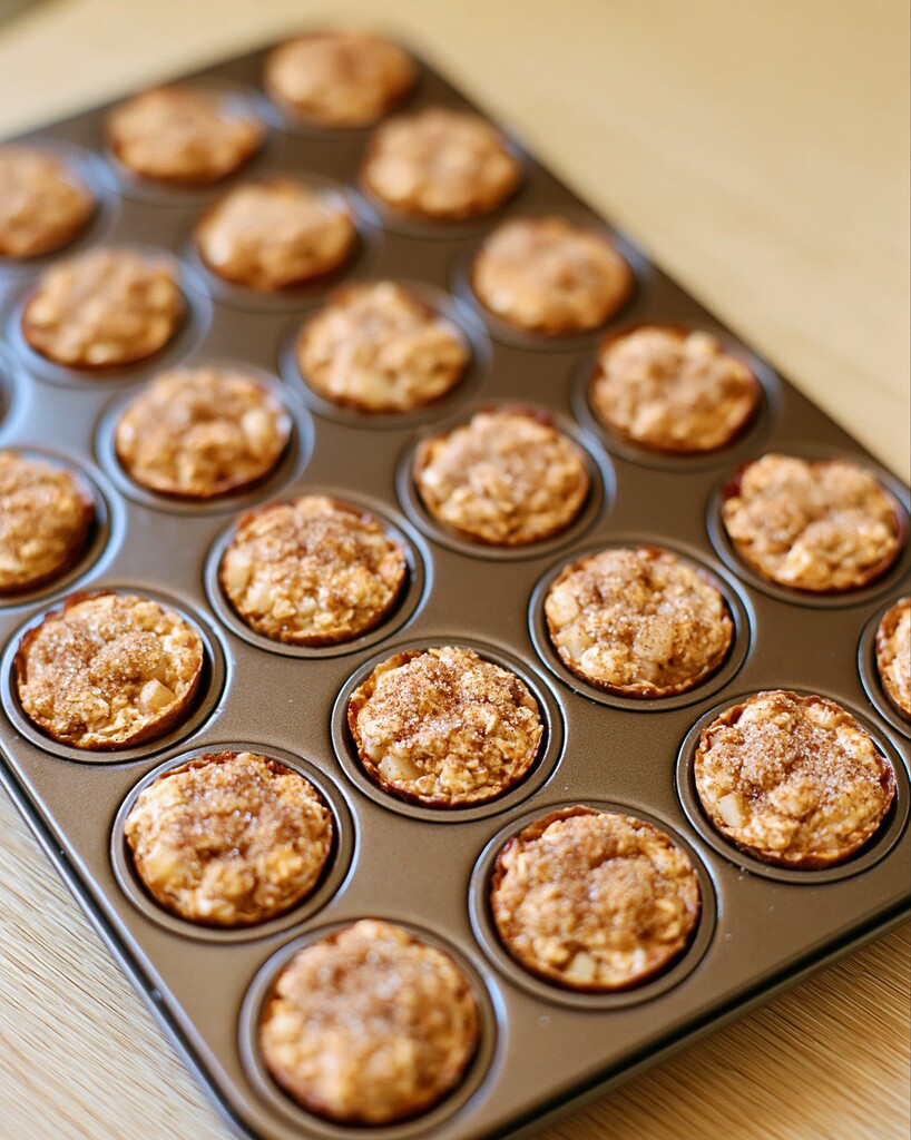 Baked apple cinnamon oatmeal bites in a muffin pan with browned edges and golden tops