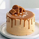 Spiced Biscoff Layer Cake with a Salted Drip A two layer Biscoff cake with a glossy salted drip and cookie crown on a white serving plate