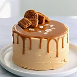 Spiced Biscoff Layer Cake with a Salted Drip A two layer Biscoff cake with a glossy salted drip and cookie crown on a white serving plate