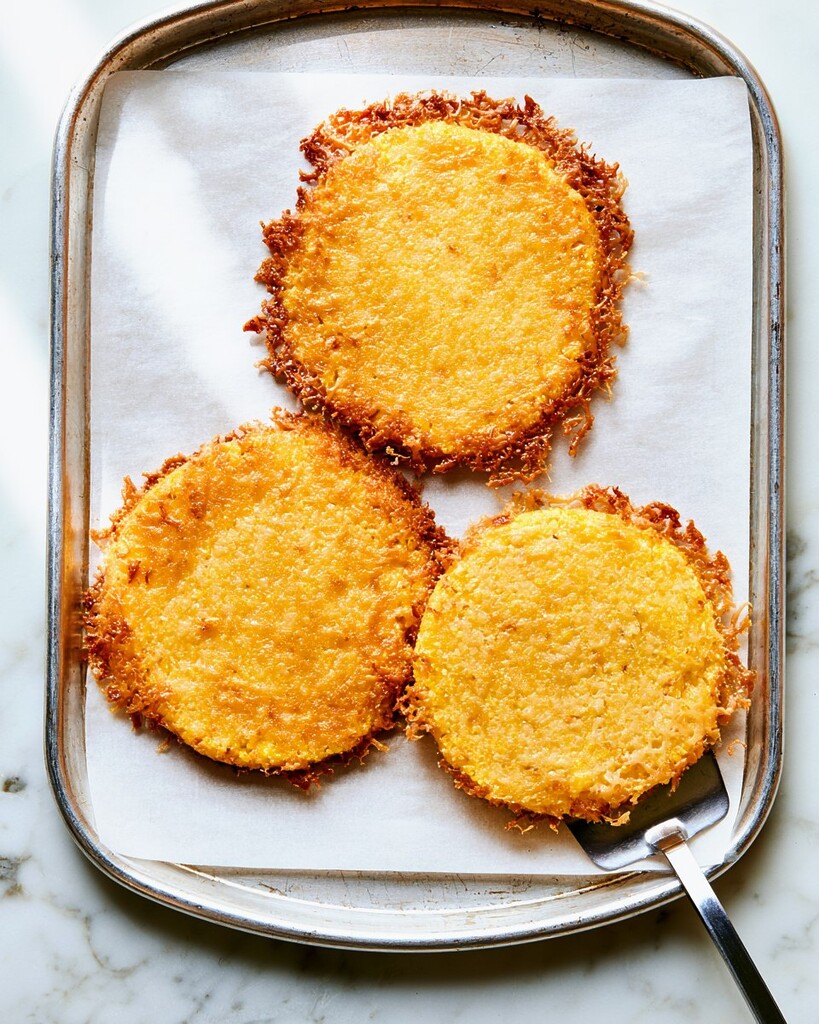 Baked polenta rounds on a sheet pan with brown and crispy melted cheese edges