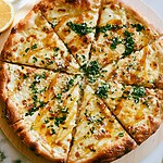 Hot Honey Lemon Pizza: A Sweet and Spicy White Pie Baked hot honey lemon pizza cut into slices on a wooden board with melted cheese, parsley, and gleaming honey