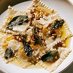 Pumpkin Wonton Ravioli with Crispy Sage and Brown Butter Pumpkin wonton ravioli topped with crispy sage leaves and pine nuts in a glossy brown butter sauce