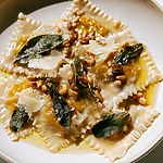 Pumpkin Wonton Ravioli with Crispy Sage and Brown Butter Pumpkin wonton ravioli topped with crispy sage leaves and pine nuts in a glossy brown butter sauce