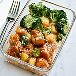Sweet chili chicken arranged over coconut rice with broccoli, pineapple, sesame, and scallions in a glass bowl