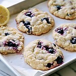 Baked lemon blueberry cookies with light surfaces and golden edges resting on a parchment-lined pan