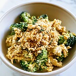 A shallow bowl of creamy chicken and broccoli in a thick cheddar sauce, topped with golden toasted panko and fresh thyme leaves