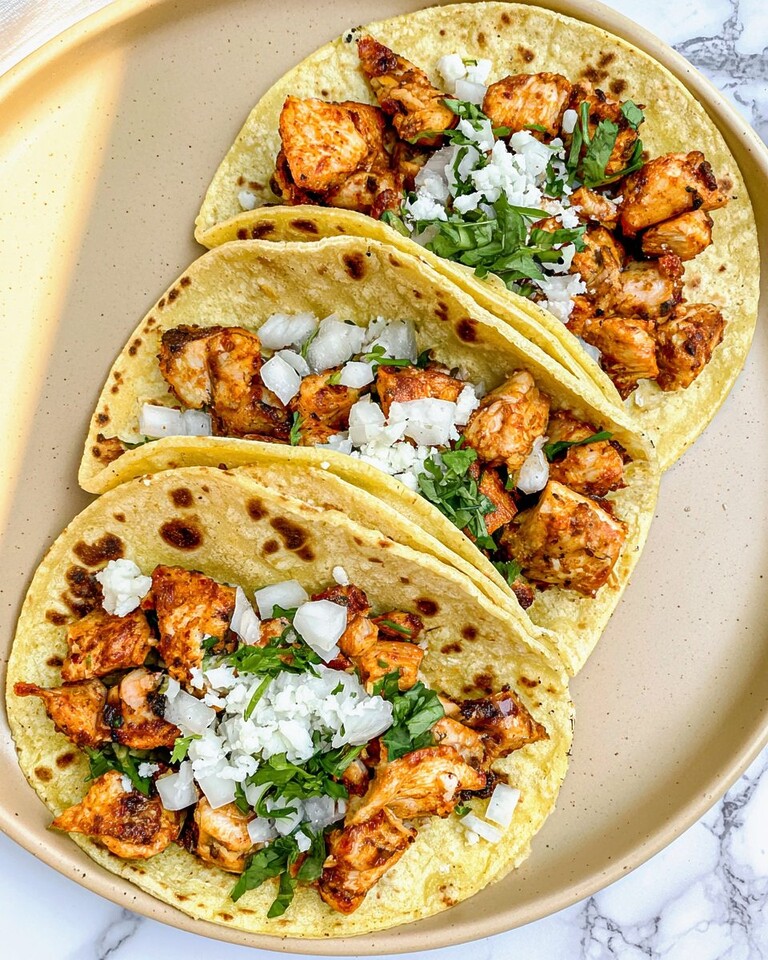 Skillet-Crisped Chicken Street Tacos Without a Grill Skillet-crisped chicken street tacos on a light plate topped with diced white onion, cilantro, and crumbled cotija cheese