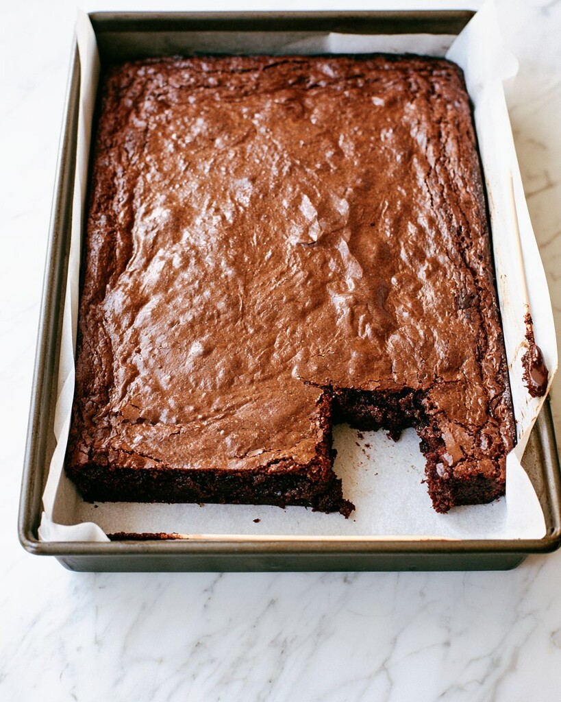 Baked brownie base in a parchment-lined baking pan