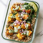 Glass meal-prep container layered with brown rice, curried chicken, red onions, and cilantro