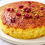 Close up of crispy golden rice crust sprinkled with bright red barberries and green pistachios