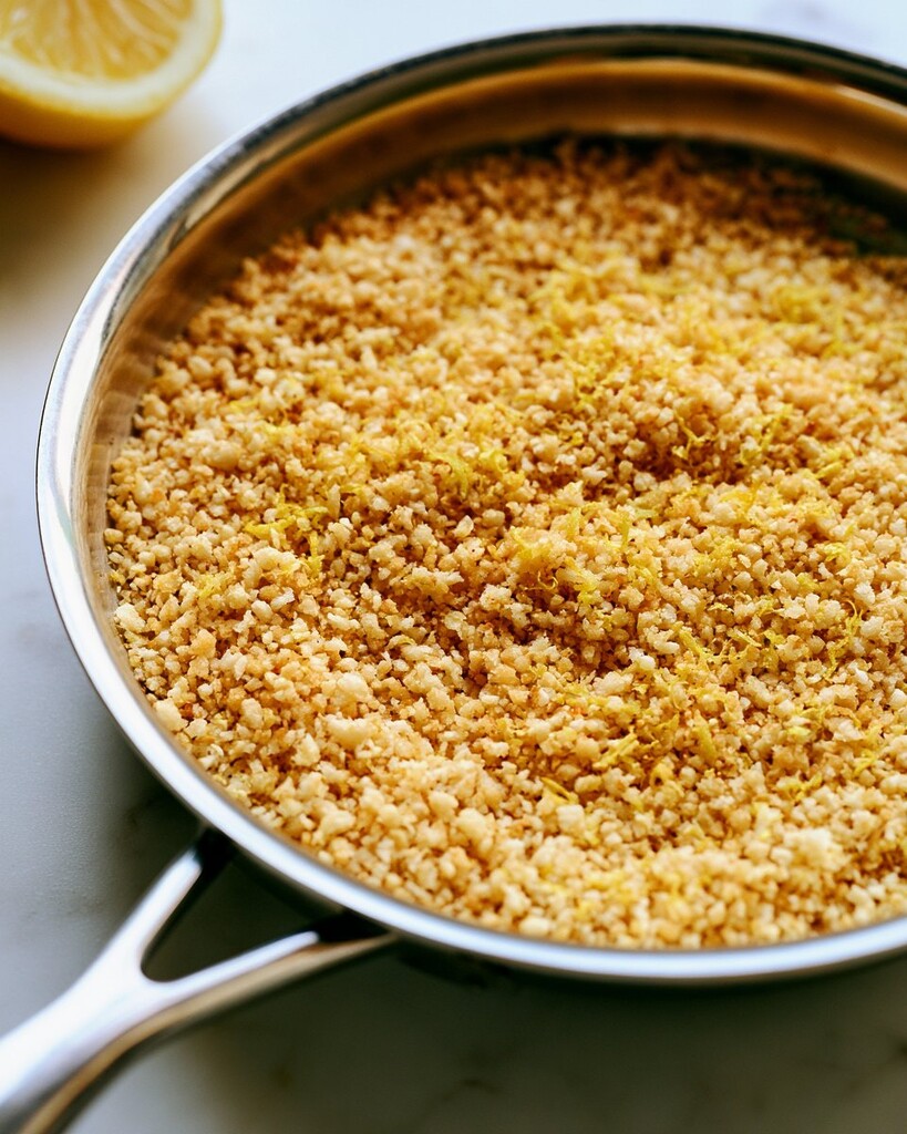 Panko breadcrumbs toasting in a metal skillet until golden brown