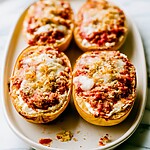 Baked spaghetti squash lasagna boats on a white plate with melted cheese and golden panko crumbs