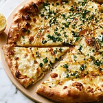 Hot honey lemon pizza on a wooden plate with slices pulled apart showing browned cheese and green herbs