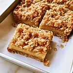 Cut lemon bar squares showing distinct creamy layers and crumb topping resting on parchment paper