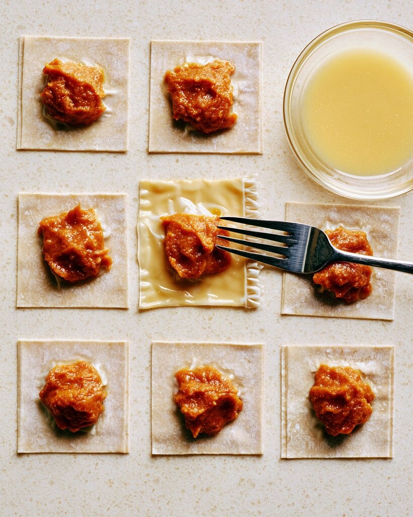 Small mounds of orange pumpkin filling centered on square wonton wrappers