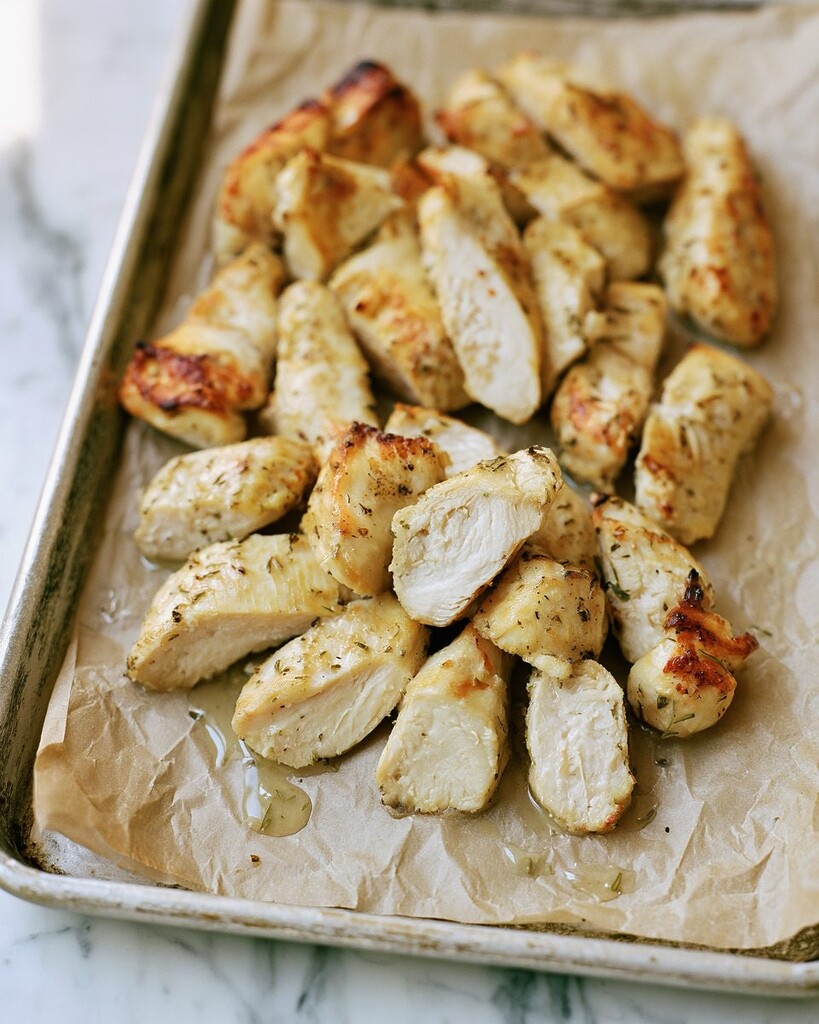 Golden roasted chicken pieces spread across a parchment-lined metal baking sheet