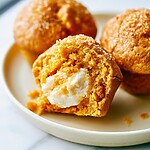 Brown Butter Pumpkin Cream Cheese Muffins A halved brown butter pumpkin muffin on a plate revealing a distinct white cream cheese center