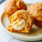 Brown Butter Pumpkin Cream Cheese Muffins A halved brown butter pumpkin muffin on a plate revealing a distinct white cream cheese center