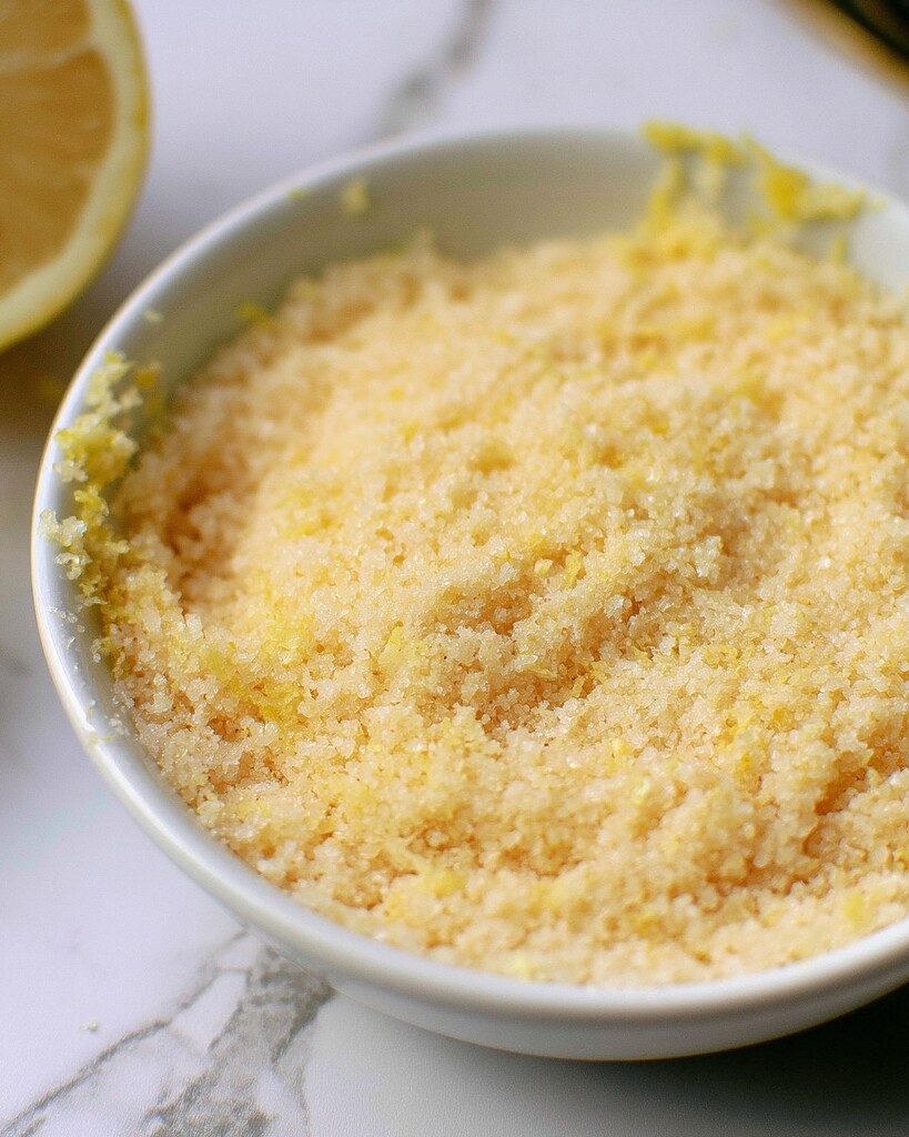 Granulated sugar mixed with yellow lemon zest inside a small bowl