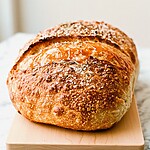 Hot Honey-Brushed Roasted Garlic Bread: No-Knead Dutch Oven Method Whole round loaf of hot honey-brushed roasted garlic bread with a shiny blistered crust sprinkled with flaky sea salt and rosemary