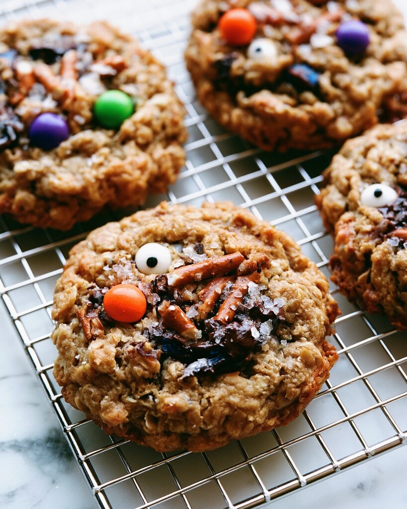 Close-up of baked cookies topped with sea salt and pretzels resting on a metal cooling rack