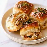 Warm chipotle chicken sliders sliced and arranged on a serving plate with melted cheese and fresh herbs.