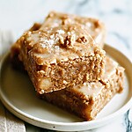 Stacked pieces of glazed brown butter apple blondies on a light plate