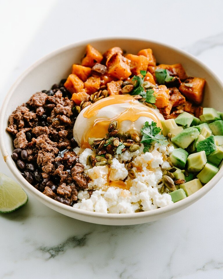 Sweet-Heat Hot Honey Beef and Sweet Potato Bowls Hot honey beef and sweet potato bowl garnished with avocado, cheese, seeds, and cilantro