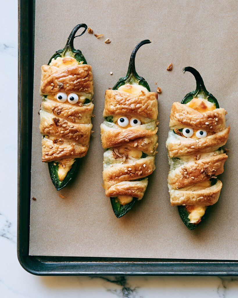 Golden brown mummy jalapeño poppers arranged on a baking sheet