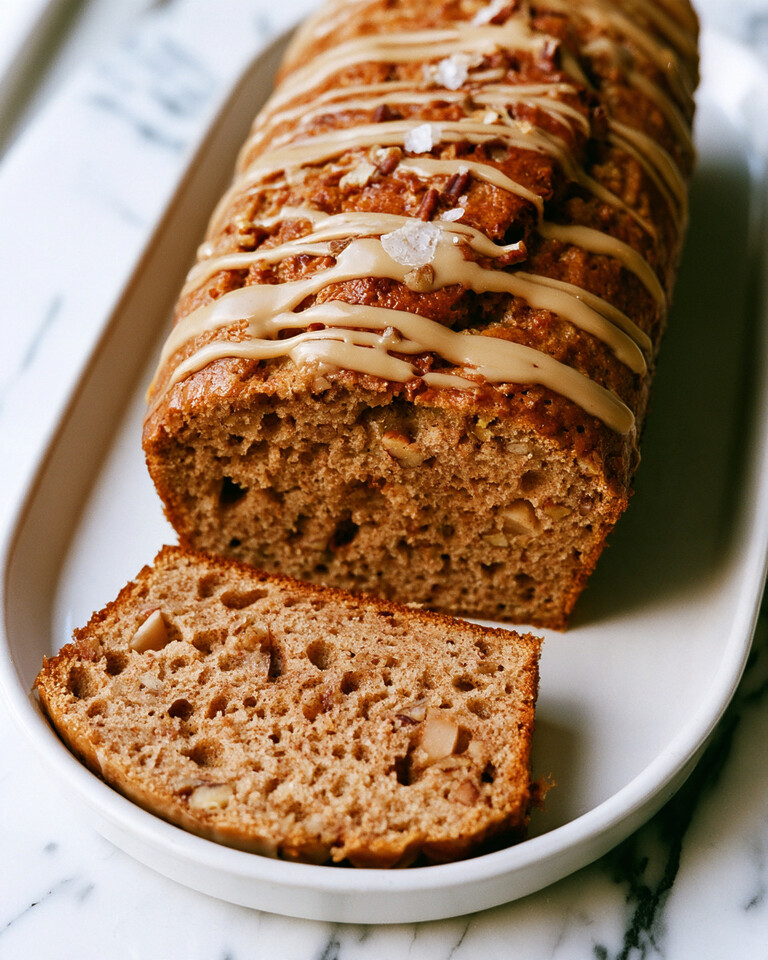 One-Bowl Apple Spice Cake with Deep Caramelized Flavor Sliced one-bowl apple spice cake on a white plate showing diced apples, nuts, and a shiny maple glaze