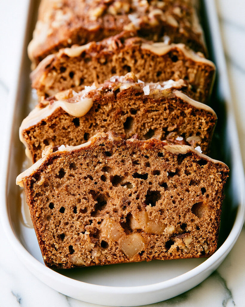 Close-up of a spiced apple cake slice showing a moist brown crumb and fresh apple chunks