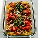 Spaghetti Squash and Turkey Meal-Prep Bowls with Chili-Lime Pepitas Glass meal-prep bowl layered with roasted spaghetti squash strands, turkey tomato sauce, cotija cheese, and toasted pumpkin seeds