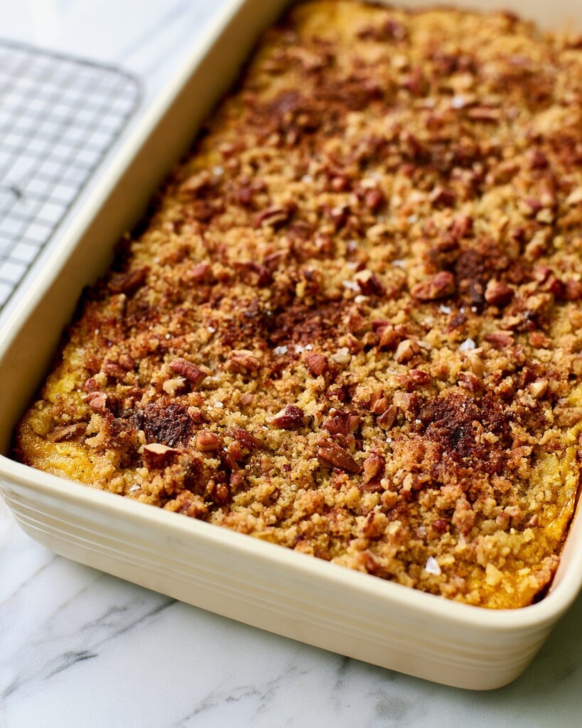Golden baked pumpkin dump cake resting in a ceramic dish