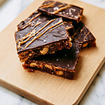 Halved pieces of date bark revealing thick layers of sticky dates, peanuts, and dark chocolate
