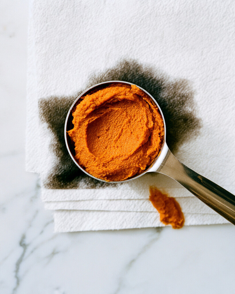 Thickened pumpkin puree in a measuring cup resting on paper towels